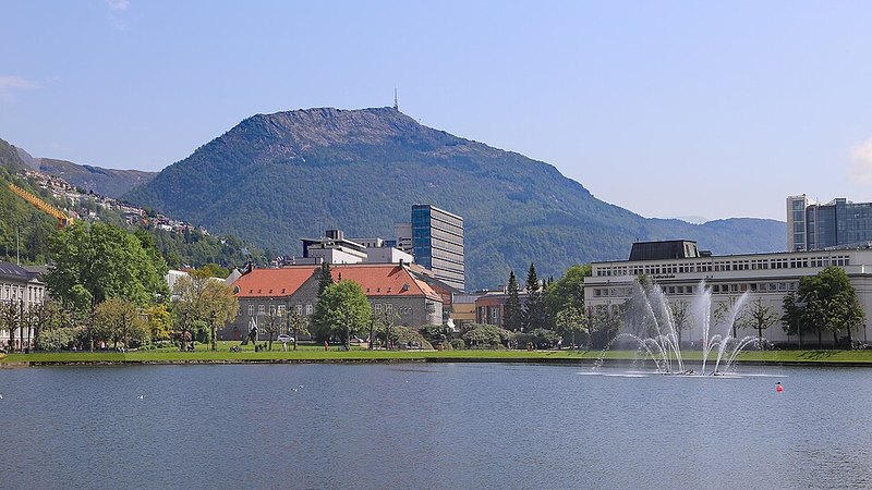 Lakefront fountain, city buildings, and mountains in Bergen, Norway.