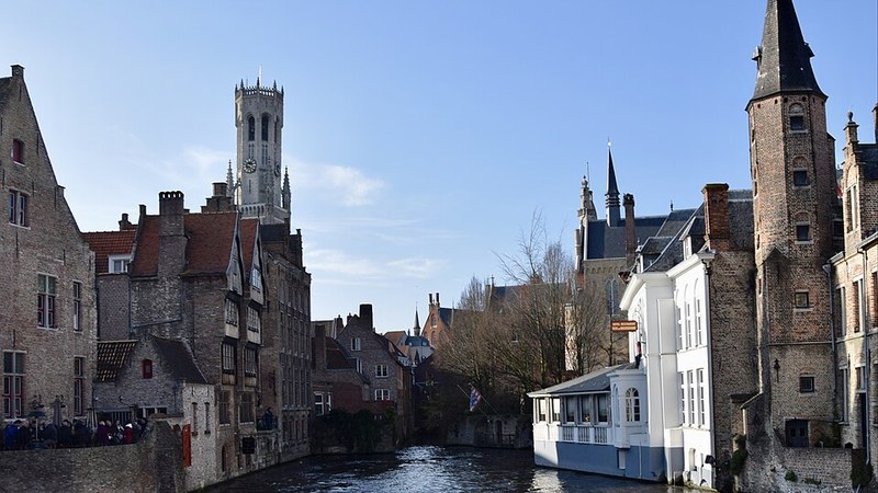 Canal, historic buildings, and the Belfry of Bruges, Belgium.