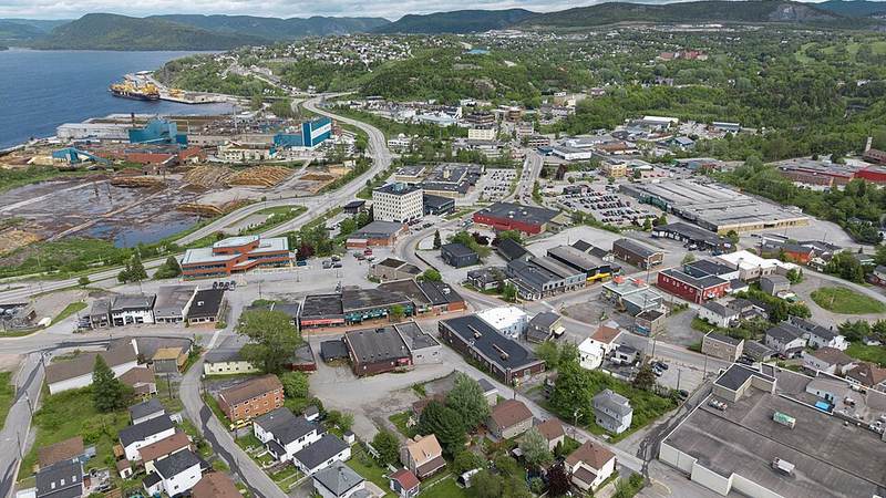 Aerial view of downtown Corner Brook, Newfoundland and Labrador, with the waterfront and green hills beyond.