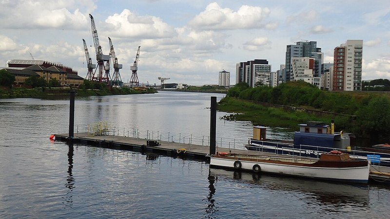 River Clyde waterfront with boats, dockyard cranes and buildings in Glasgow