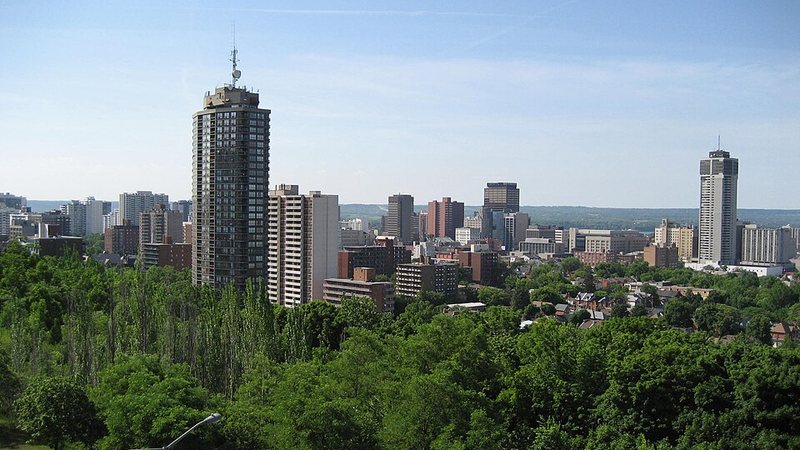 Downtown Hamilton skyline above a green tree canopy in Ontario.