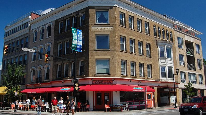 Historic downtown street corner with outdoor dining in Ithaca, New York.