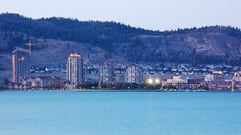 Kelowna waterfront towers across Okanagan Lake, with wooded hills behind the city.
