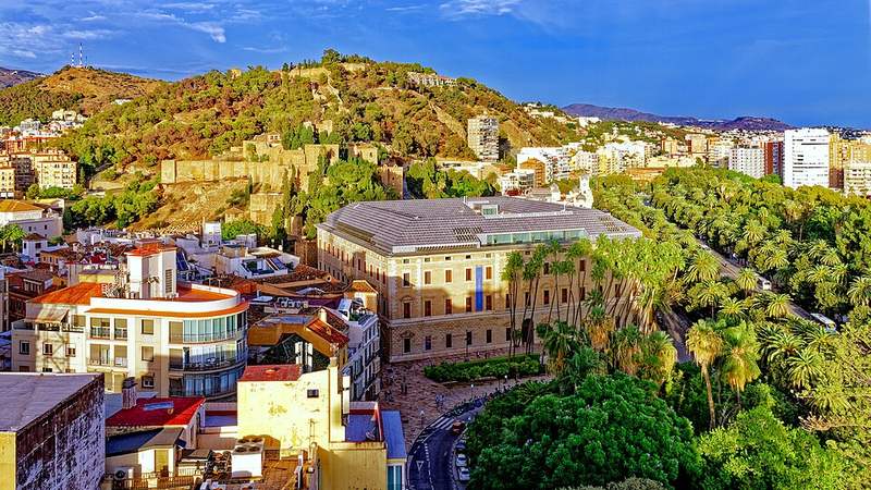 Málaga, Spain, with hillside fortifications and palm-lined streets.