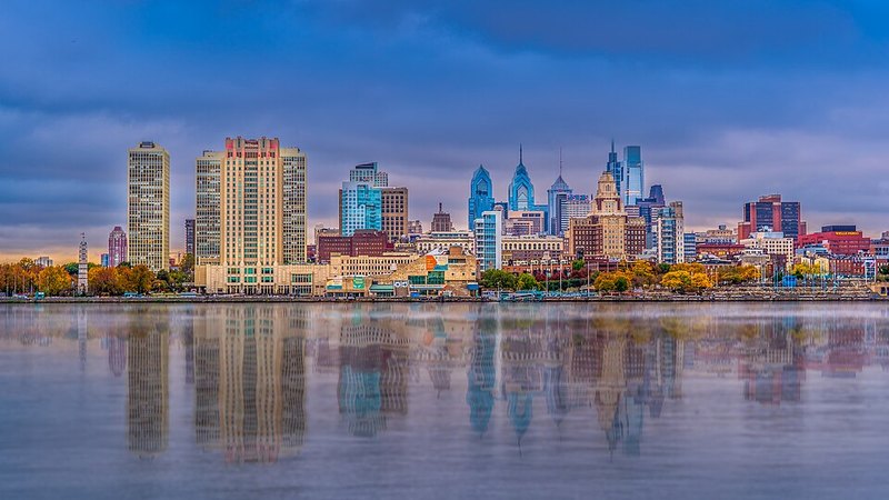 Philadelphia skyline and Delaware River waterfront at sunset.
