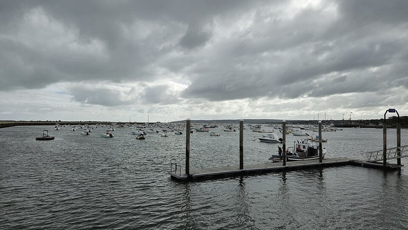 Boats and docks in Plymouth Harbor, Massachusetts, beneath a cloudy sky.