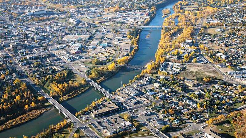 Aerial view of downtown Red Deer, Alberta, with bridges crossing the Red Deer River amid autumn trees.
