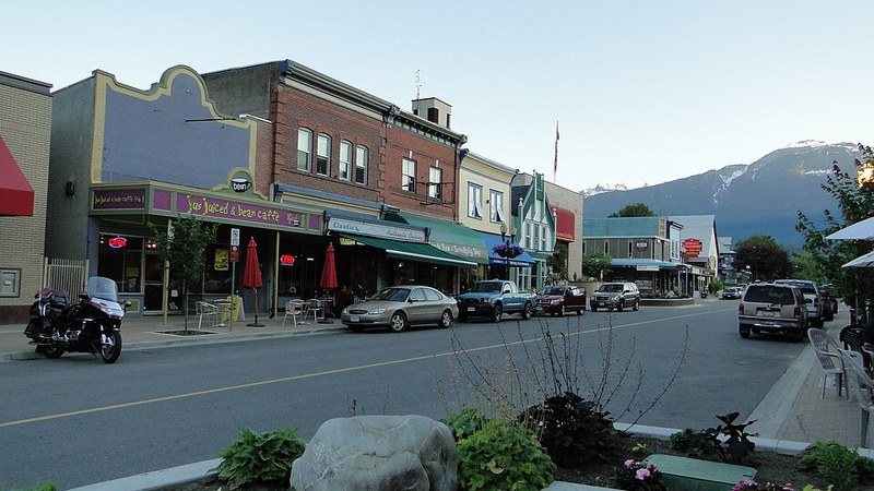 Historic downtown Revelstoke storefronts with mountain slopes behind the street.