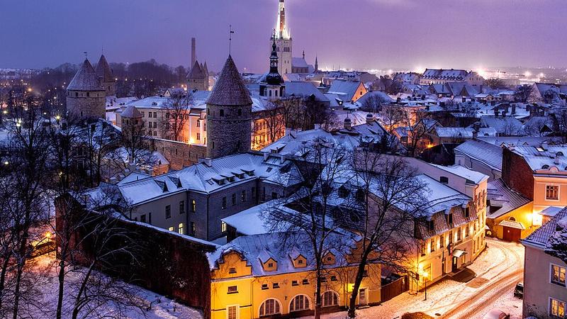 Snow-covered rooftops and towers of Tallinn's old town at night, Estonia.