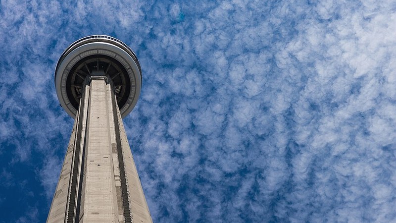 CN Tower rising into a blue, cloud-textured sky in Toronto, Ontario.
