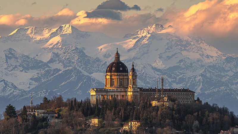 The Basilica of Superga above Turin, with snowy Alps at sunset.