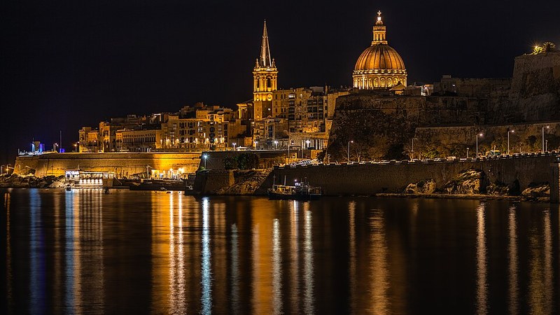 Valletta, Malta, skyline reflected in the water at night.