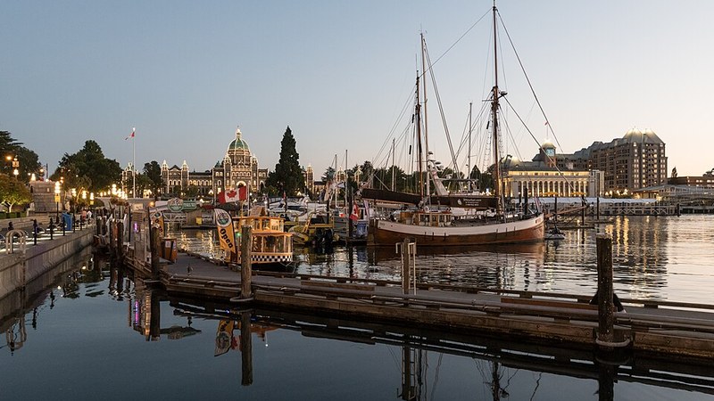Boats in Victoria Inner Harbour at dusk with the illuminated British Columbia Parliament Buildings.