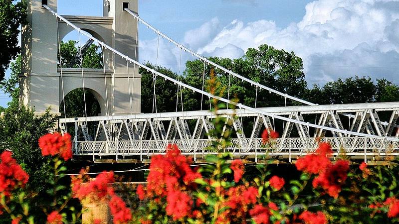 Waco Suspension Bridge framed by red flowers in Texas.