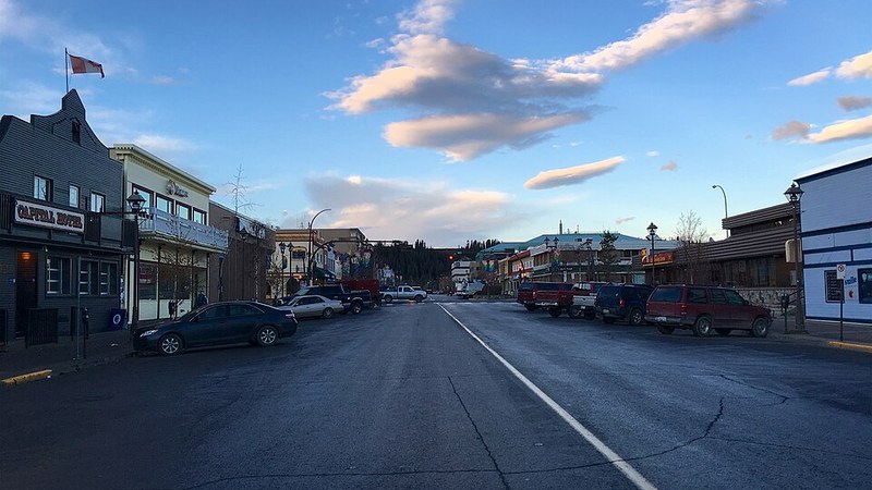 Main Street in downtown Whitehorse, Yukon, beneath blue sky and scattered clouds.